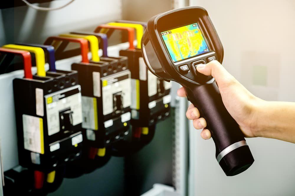 Technician use thermal imaging camera to check temperature in factory